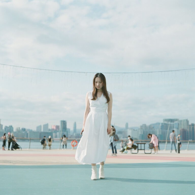 Woman in white dress standing on the colorful playground at East Coast Park Hong Kong with city skyline in the background