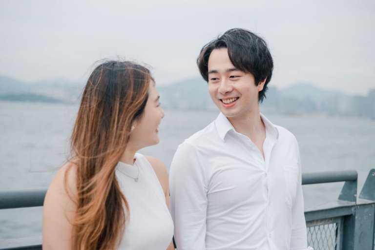 Romantic prewedding portrait of a young couple sharing an intimate laugh together at their alma mater in Hong Kong, captured in natural spontaneous joy, part of a seaside series (5/14).