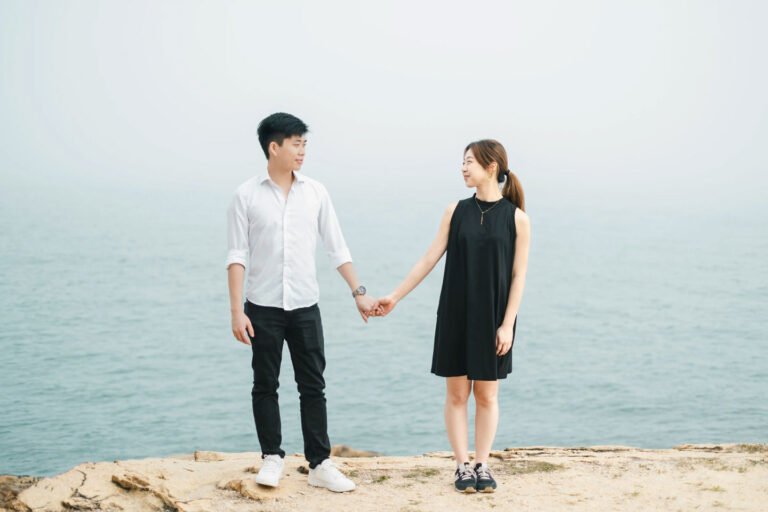 Couple holding hands on seaside cliff, romantic engagement photography at Lei Yue Mun Hong Kong